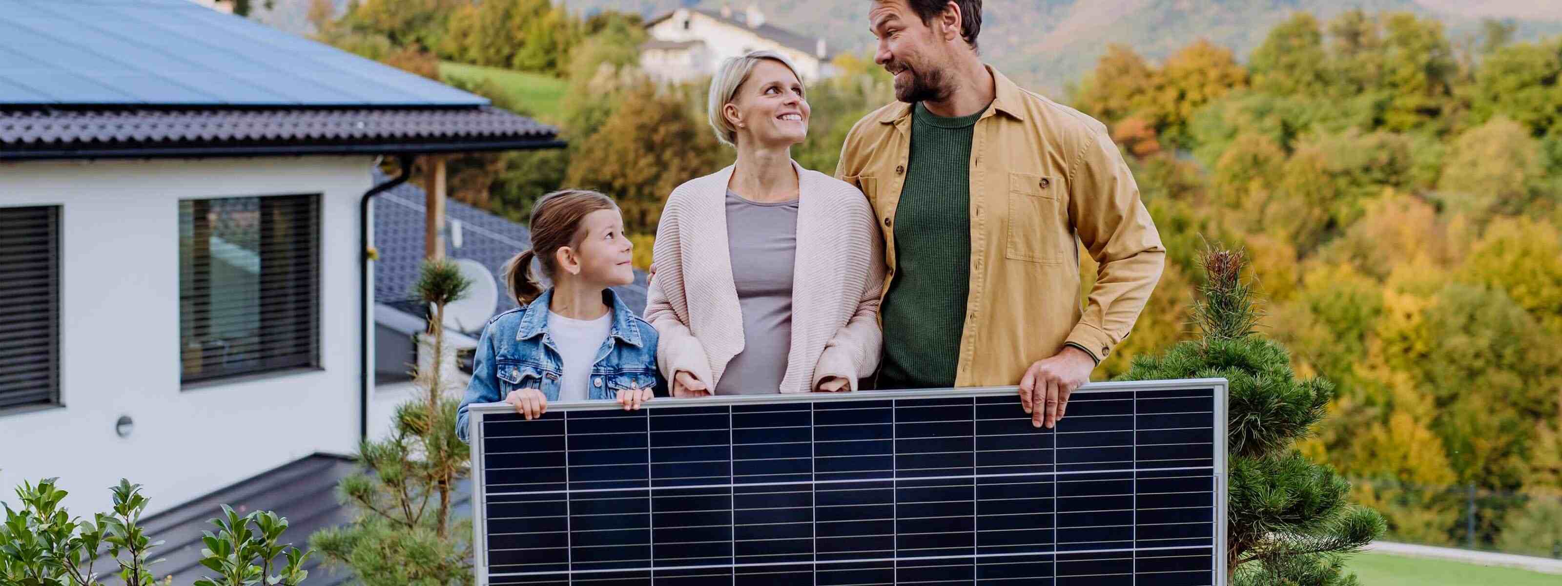 Eine Familie hält eine Solaranlage vor ihrem Haus. Beitrag zur Energiewende und Kostenersparnis durch Photovoltaik